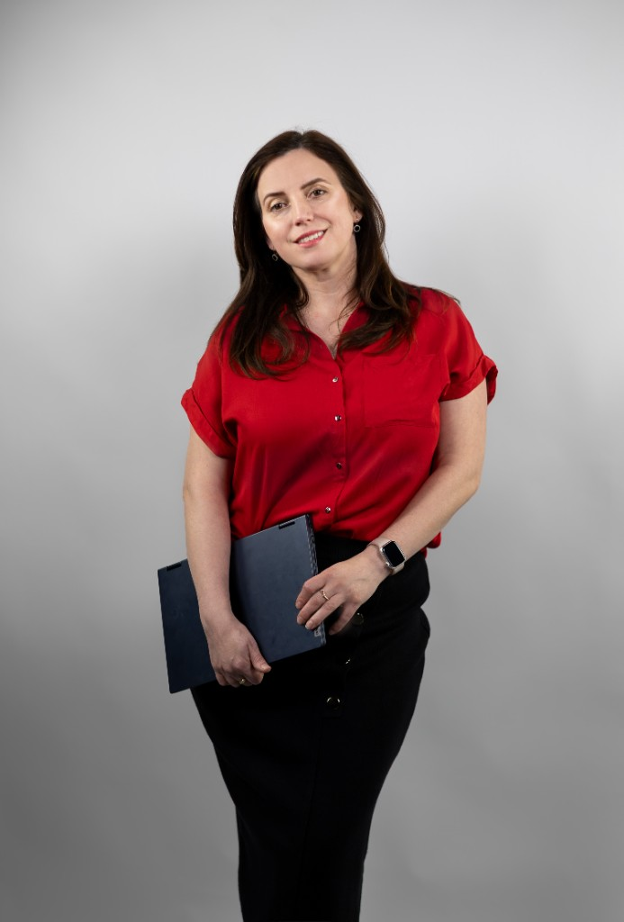 Liana Terec — portret profesional, cămașă roșie, ținând un laptop